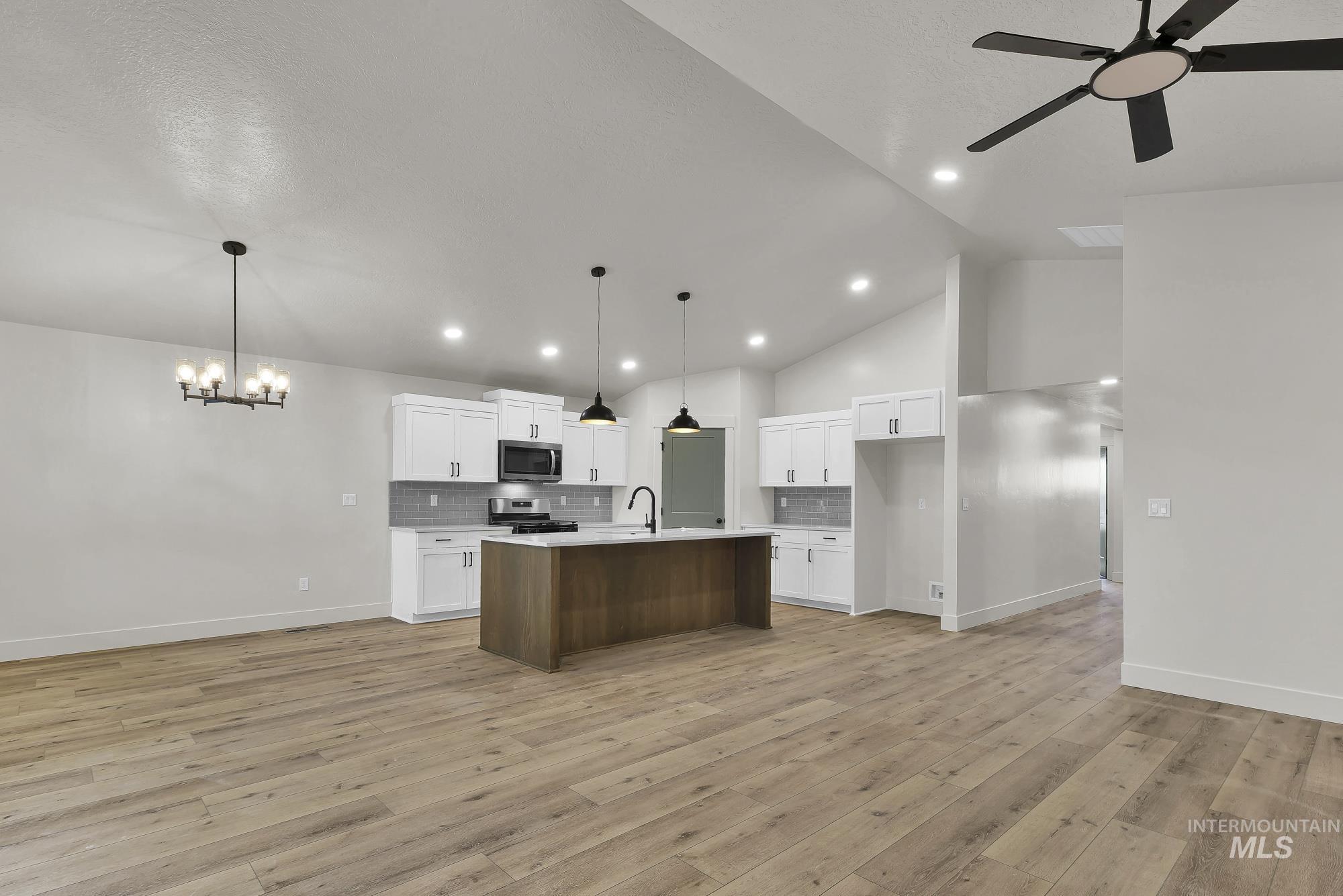 1130 Velvet Loop Wilder, ID 83676 - Photo 7 of 35 Open-concept living area featuring wood-finish flooring, a contemporary kitchen, vaulted ceilings, recessed lighting, and a modern ceiling fan