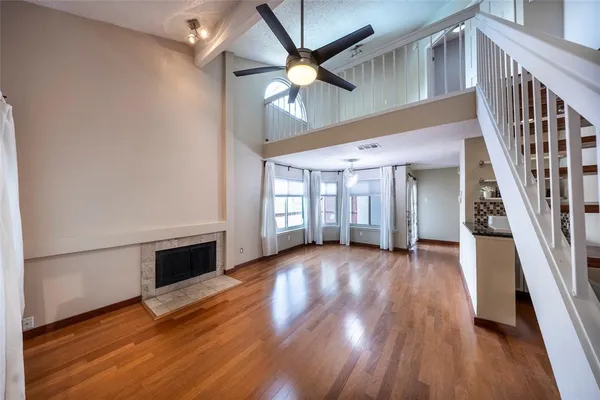 a view of an empty room with wooden floor a ceiling fan and windows