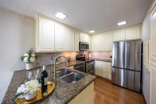 a kitchen with stainless steel appliances granite countertop a sink a stove a microwave a counter space and cabinets