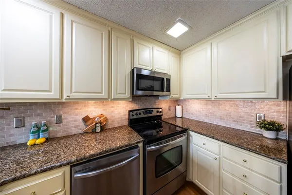 a kitchen with granite countertop a sink stainless steel appliances and cabinets