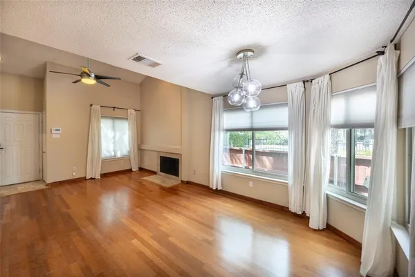 a view of a livingroom with a chandelier wooden floor and windows