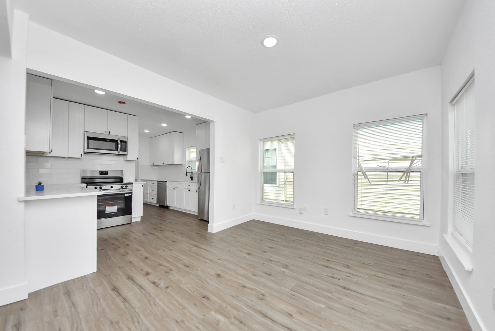 1203 West 6th Street Freeport, TX 77541 - Photo 15 of 50 a kitchen with stainless steel appliances a stove top oven a sink dishwasher and a refrigerator with wooden floor