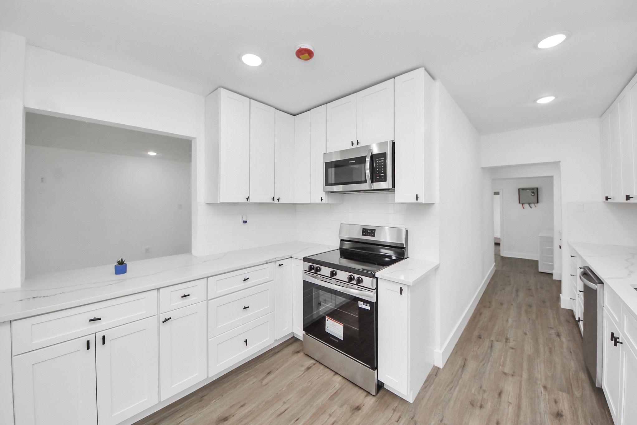 1203 West 6th Street Freeport, TX 77541 - Photo 20 of 50 a kitchen with stainless steel appliances a white stove top oven a sink dishwasher and a microwave with wooden floor