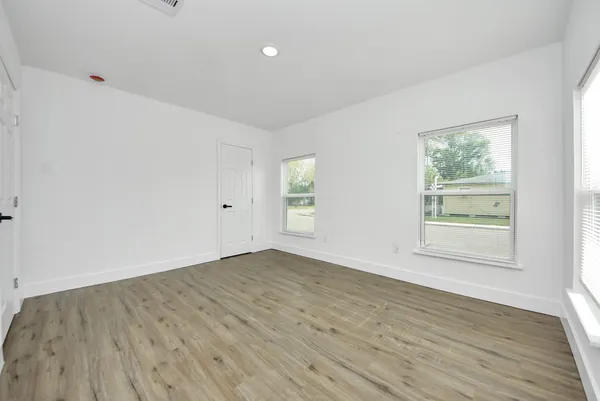 an empty room with wooden floor and windows