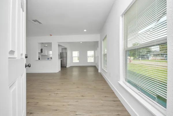 a view of a hallway with wooden floor and windows