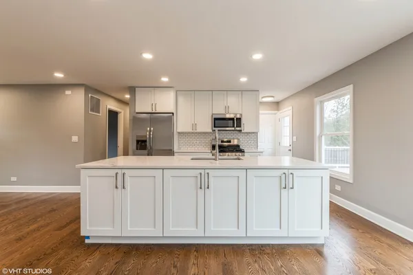 a kitchen with stainless steel appliances granite countertop a white cabinets and a wooden floor