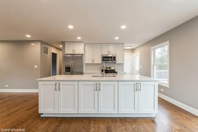 a kitchen with stainless steel appliances granite countertop a white cabinets and a wooden floor
