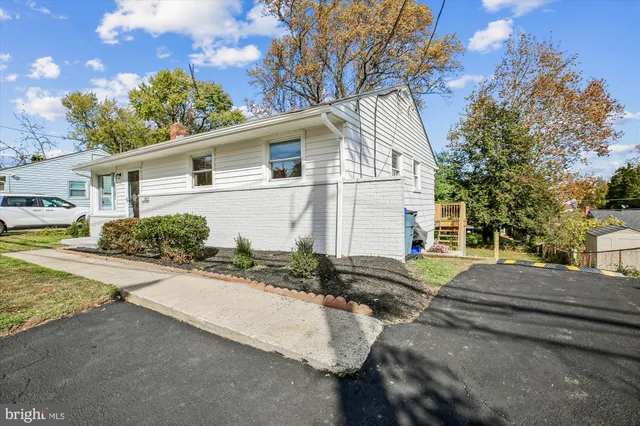 a view of a white house next to a road and yard