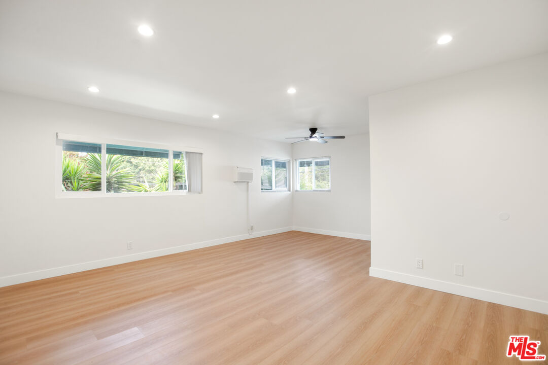 an empty room with wooden floor and windows
