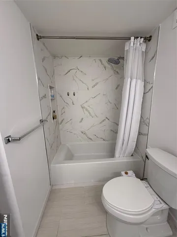 a white toilet sitting next to a bath tub and a shower