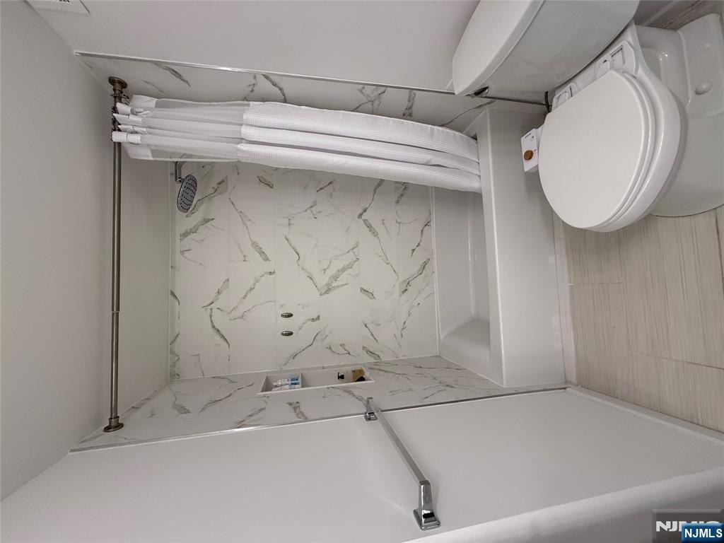 1055 River Road, Unit 504 Edgewater, NJ 07020 - Photo 13 of 17 a white toilet sitting next to a bath tub and a shower