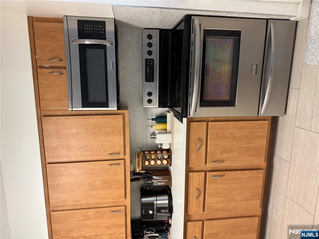 1055 River Road, Unit 504 Edgewater, NJ 07020 - Photo 9 of 17 a kitchen with stainless steel appliances granite countertop a stove microwave and cabinets