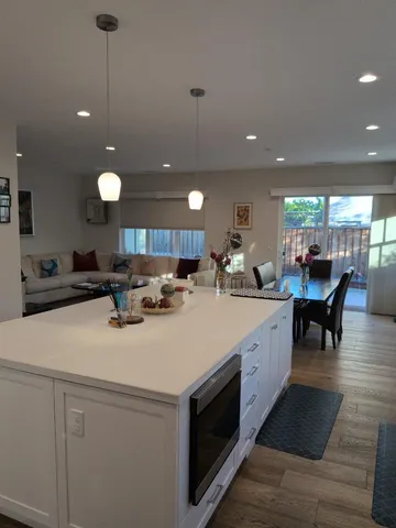 a large white kitchen with a large island oven a stove and a sink with garden view
