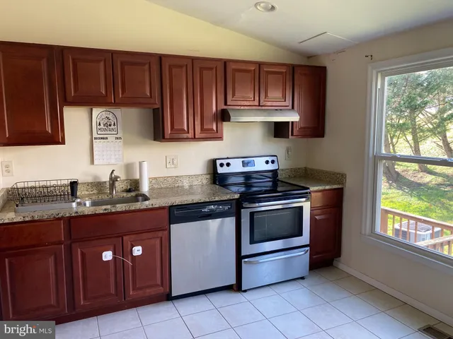 a kitchen with stainless steel appliances granite countertop wooden cabinets a stove a sink and a window