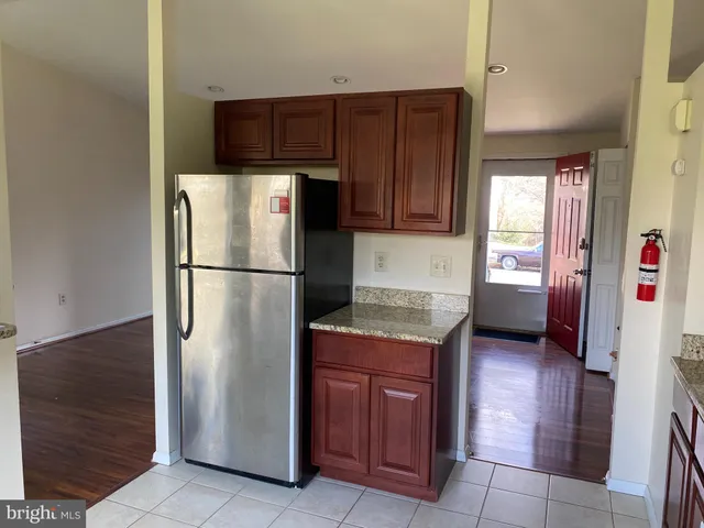 a kitchen with granite countertop wooden cabinets and a refrigerator