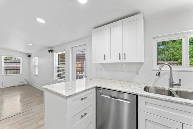 a kitchen with granite countertop white cabinets and window