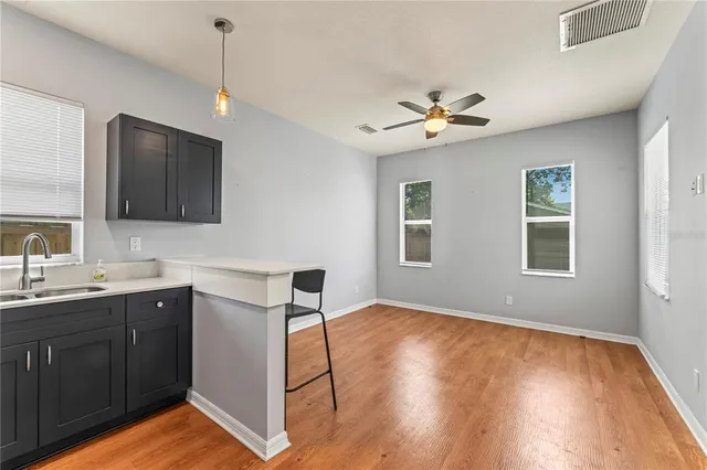 a view of a kitchen with a sink cabinet a ceiling fan and wooden floor