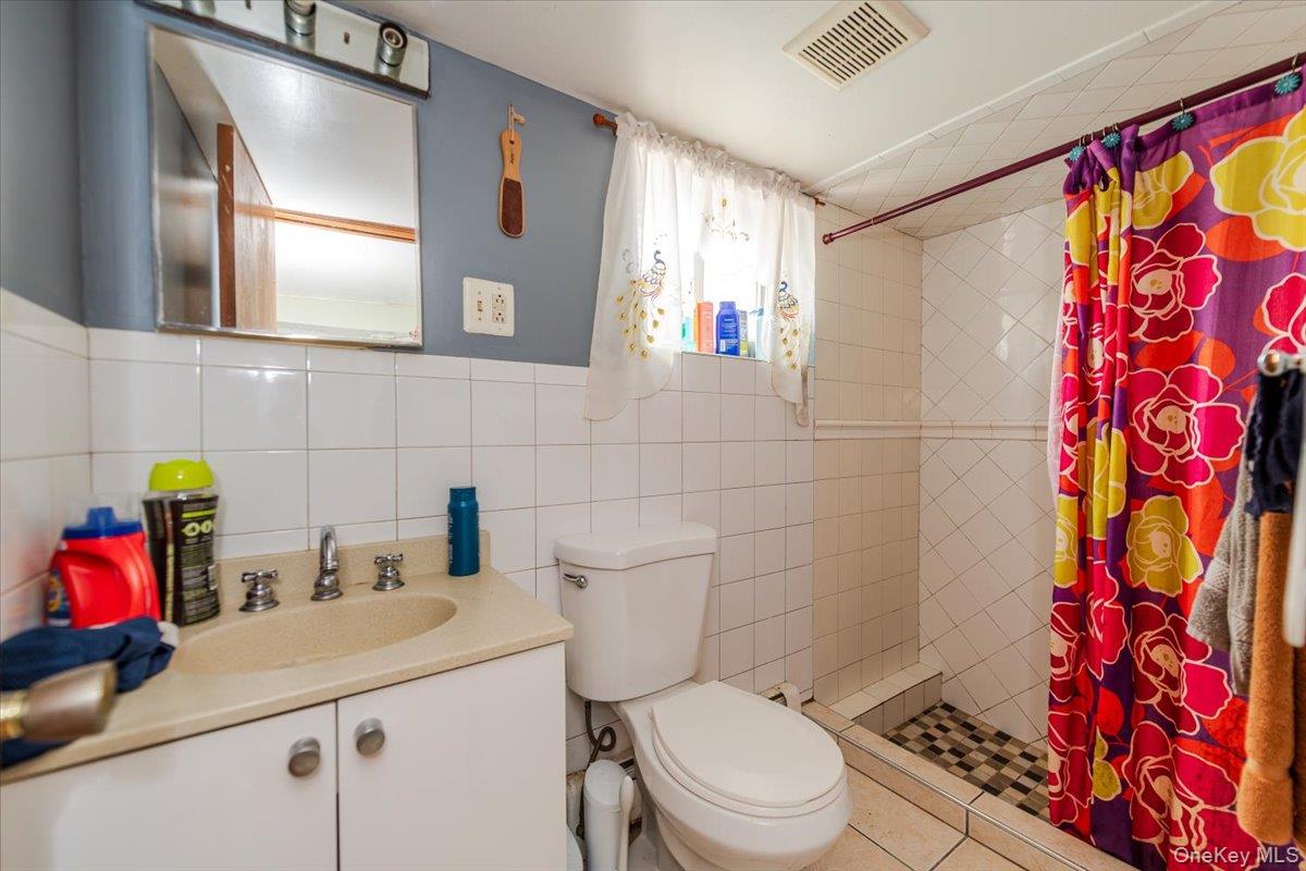 137-27 Thurston Street Queens, NY 11413 - Photo 15 of 19 Full bath featuring a stall shower, vanity, tile walls, and tile patterned flooring