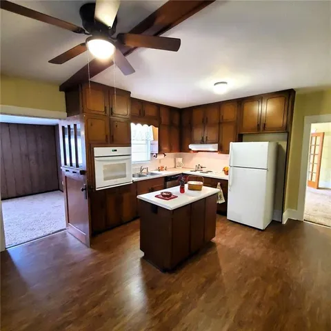 a living room with stainless steel appliances kitchen island hardwood floor and a fireplace