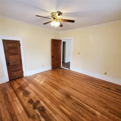 a view of empty room with wooden floor and fan