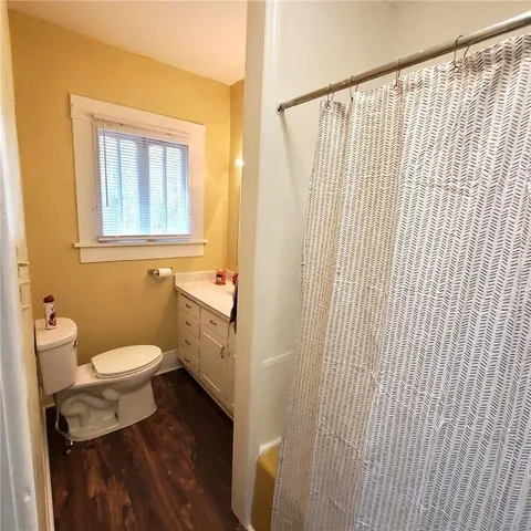 a view of an empty room with wooden floor and windows