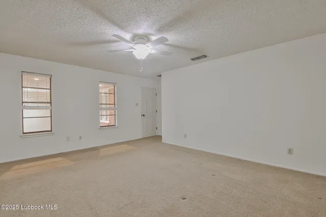 an empty room with windows and fan