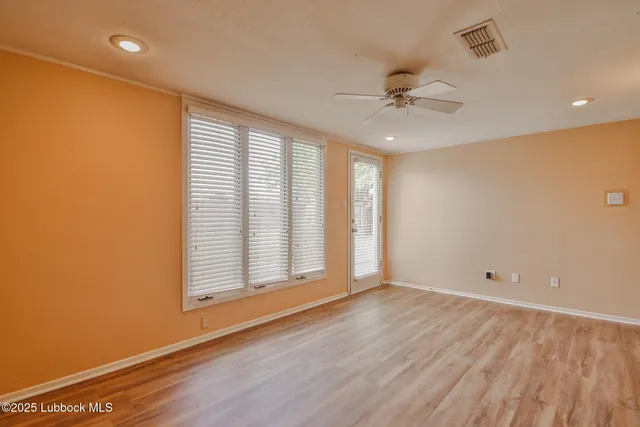 a view of an empty room with a window and wooden floor