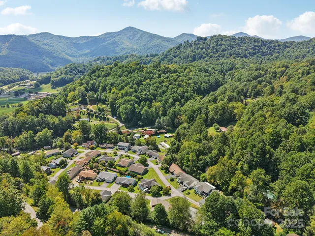 an aerial view of residential house with parking and trees