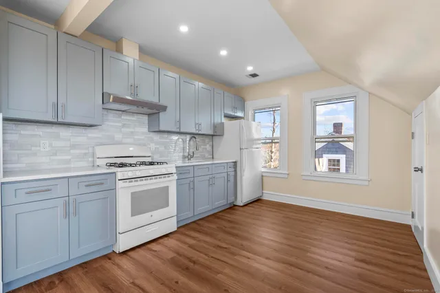 a kitchen with granite countertop white cabinets and white appliances