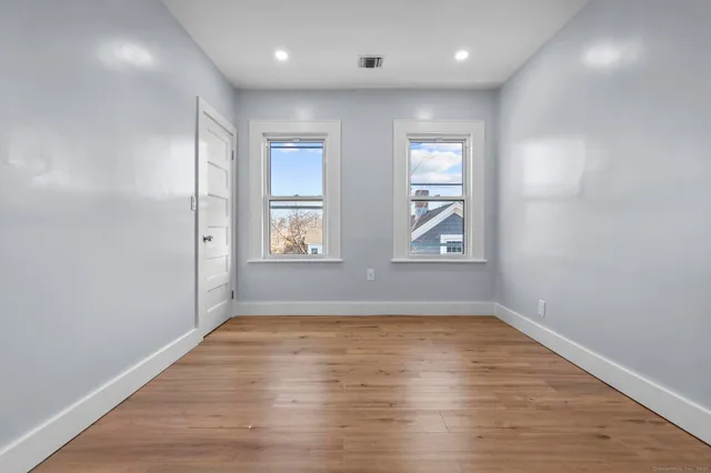 an empty room with wooden floor and windows
