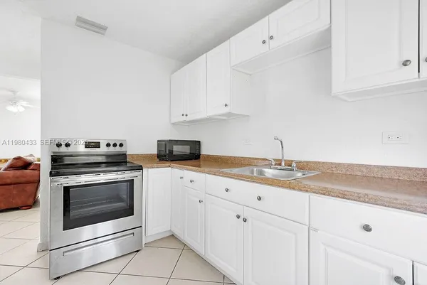 a kitchen with white cabinets and refrigerator