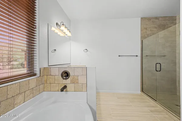 a spacious bathroom with a tub sink and mirror