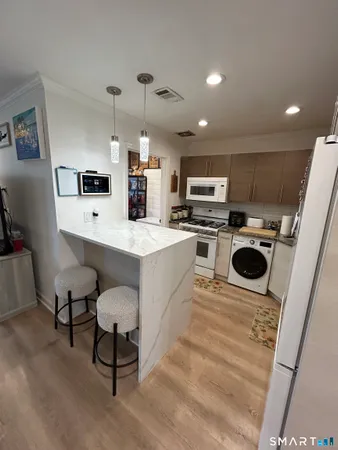 a kitchen with kitchen island a stove a microwave a sink a stove and white cabinets with wooden floor