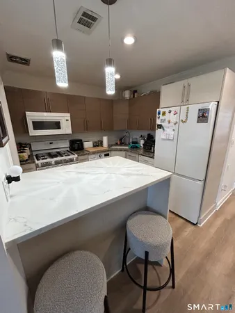 a kitchen with stainless steel appliances a refrigerator a sink a stove a microwave a dining table and chairs with wooden floor