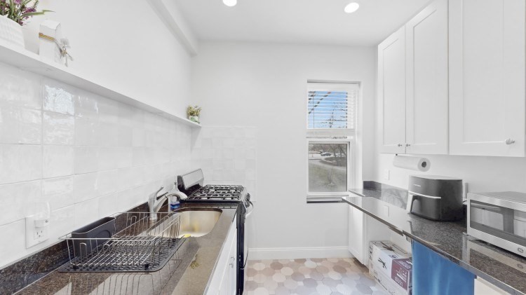 56 Charlesgate East, Unit 138 Boston, MA 02215 - Photo 3 of 17 a kitchen with granite countertop a sink a stove and cabinets