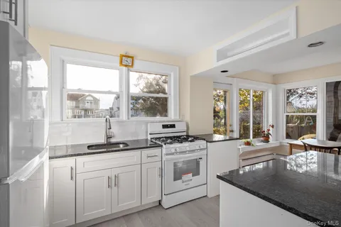 a kitchen with stainless steel appliances granite countertop a stove a sink and a granite counter tops with white cabinets