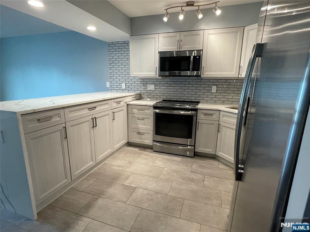 52 Reilly Court, Unit 1 Hackensack, NJ 07601 - Photo 3 of 25 a kitchen with kitchen island granite countertop a sink appliances and cabinets