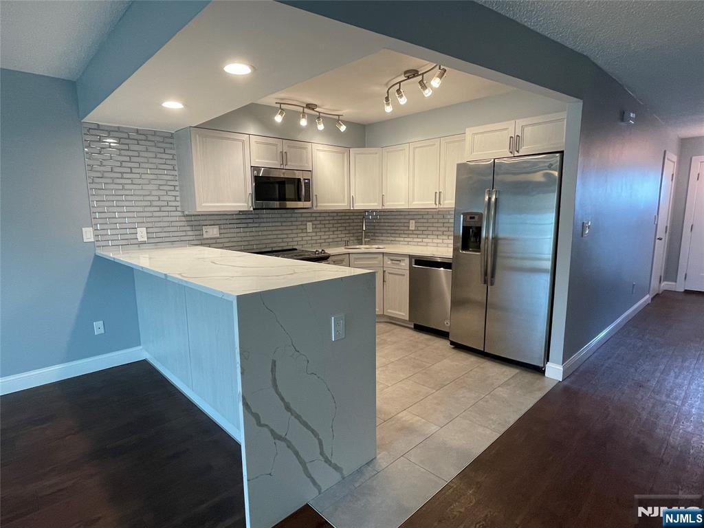 52 Reilly Court, Unit 1 Hackensack, NJ 07601 - Photo 6 of 25 a large kitchen with stainless steel appliances kitchen island a stove a refrigerator a sink dishwasher with a dining table and chairs