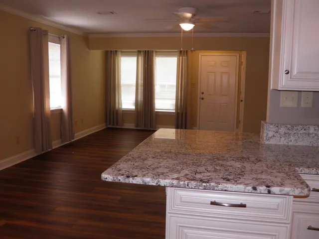 a kitchen with kitchen island granite countertop wooden floors and a sink