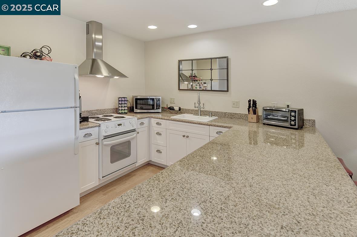2148 Golden Rain Road, Unit 1 Walnut Creek, CA 94595 - Photo 19 of 48 a kitchen with stainless steel appliances a sink a stove a refrigerator and white cabinets