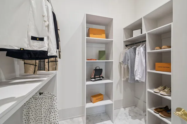 a view of walk in closet with clothes and shoes