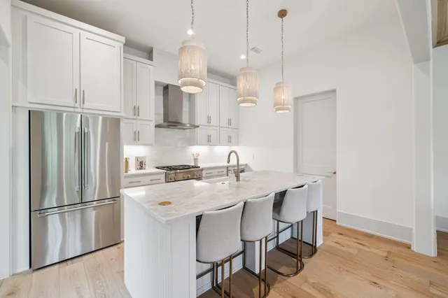 a kitchen with stainless steel appliances a refrigerator a sink a stove a dining table and chairs