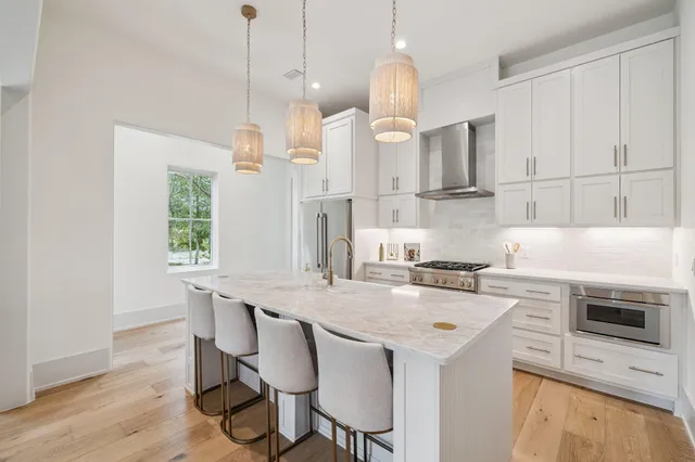 a kitchen with stainless steel appliances granite countertop a stove a refrigerator a oven a white table and chairs with wooden floor