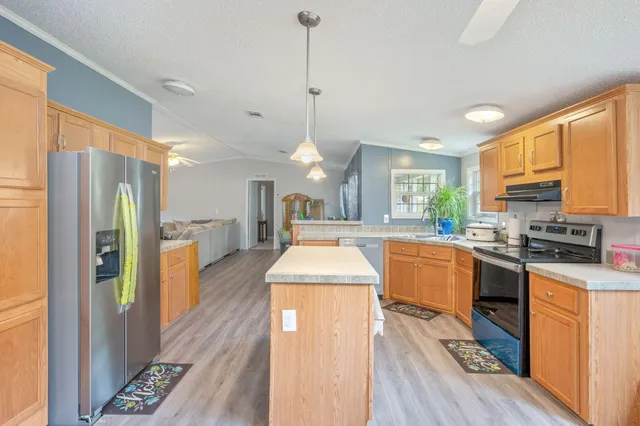 a kitchen with stainless steel appliances granite countertop sink stove refrigerator and cabinets