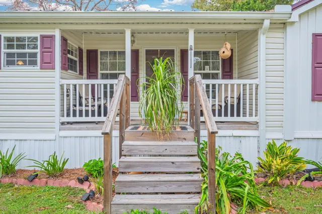 a view of a house with potted plants and a bench