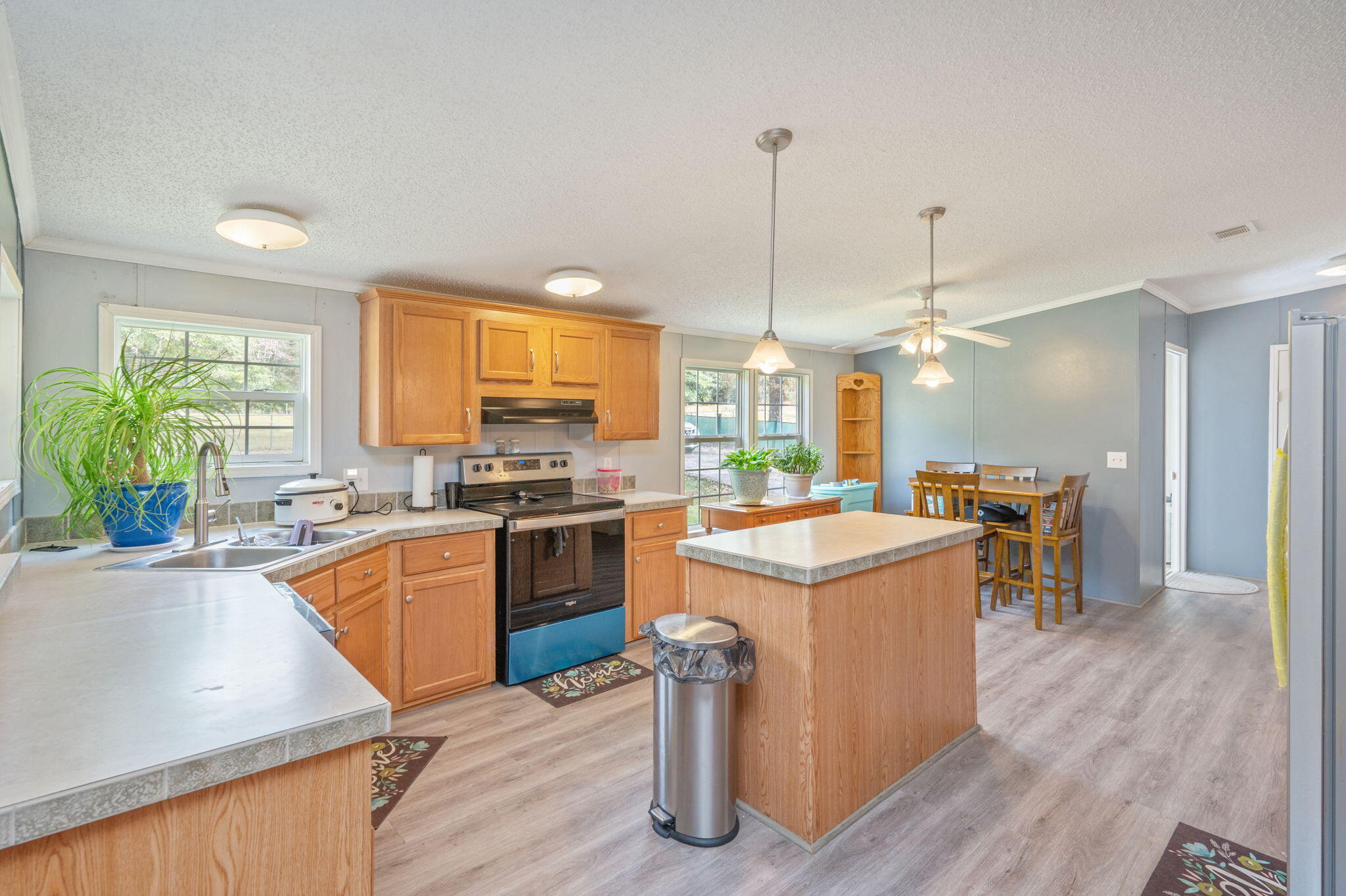 6918 Bill Lundy Road Laurel Hill, FL 32567 - Photo 6 of 27 a kitchen with a stove a refrigerator a sink dishwasher with a dining table and chairs with wooden floor