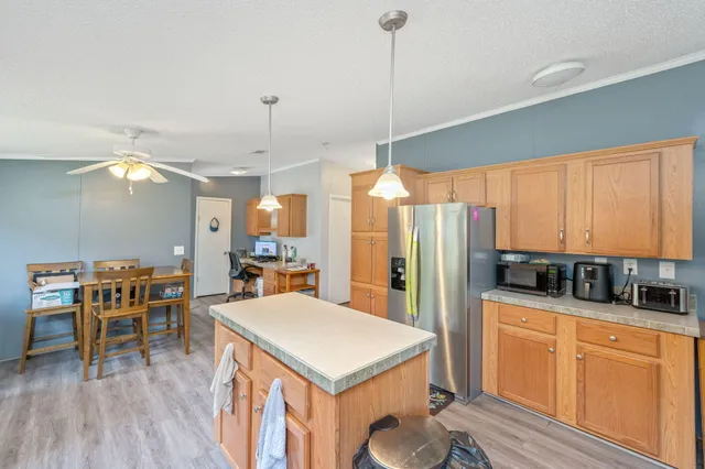 a kitchen with stainless steel appliances granite countertop a stove a refrigerator a oven a sink with island chairs and wooden cabinets