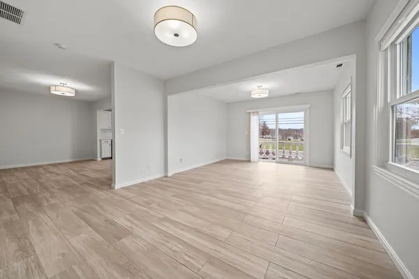 a view of an empty room with a window and wooden floor