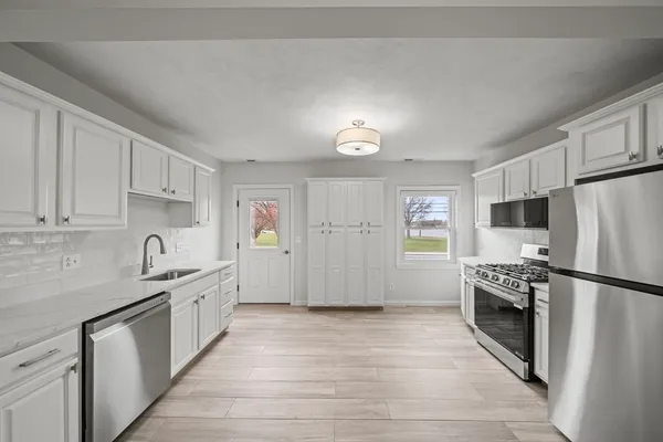 a kitchen with granite countertop a refrigerator stove top oven and sink