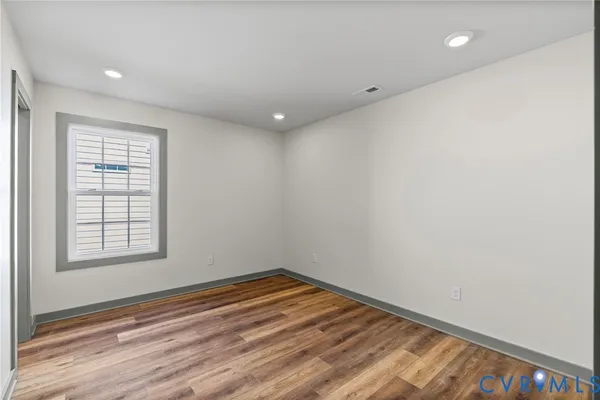 a view of an empty room with wooden floor and closet